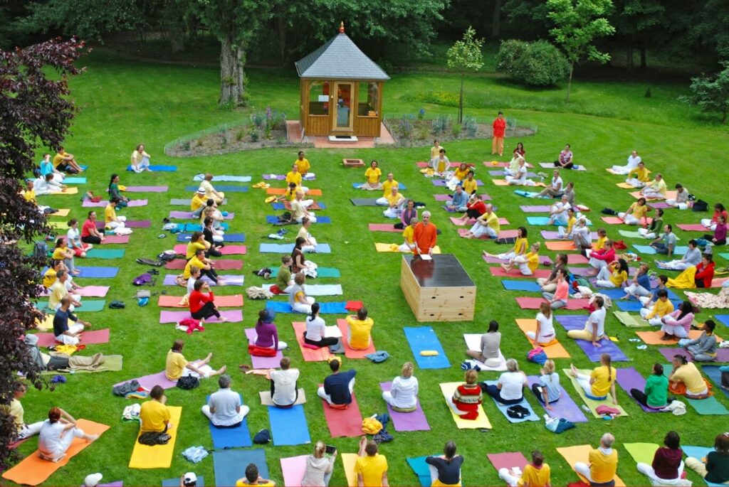 Large group of yoga practitioners on the lawn in front of the Ashram de Yoga Sivananda