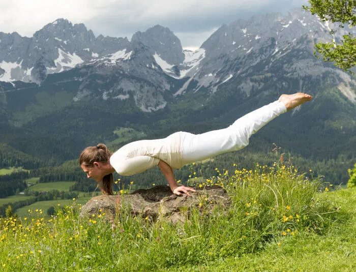 The Peacock Yoga pose with the Alps in the background