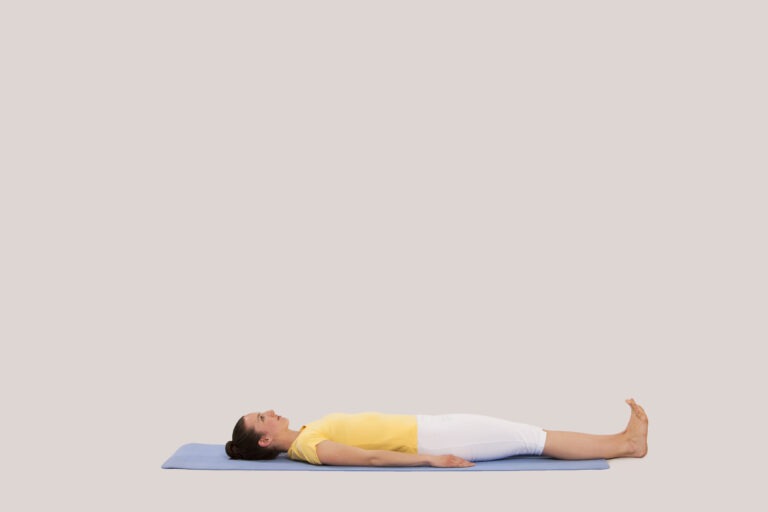Lying on your back with legs together and arms next to the body, palms facing downward